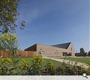 Glulam roof trusses bridge the open plan hall, reconfigurable with sliding partitions