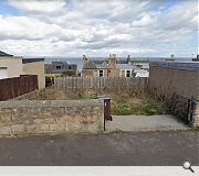 The unkempt plot sits amid a run of garages