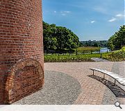 The chimney stands as a marker within the riverside landscape