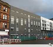 A grey complexion contrasts with the rich red sandstone of a surviving tenement